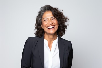 Portrait photography of a happy Peruvian woman in her 50s wearing a classic blazer against a white background