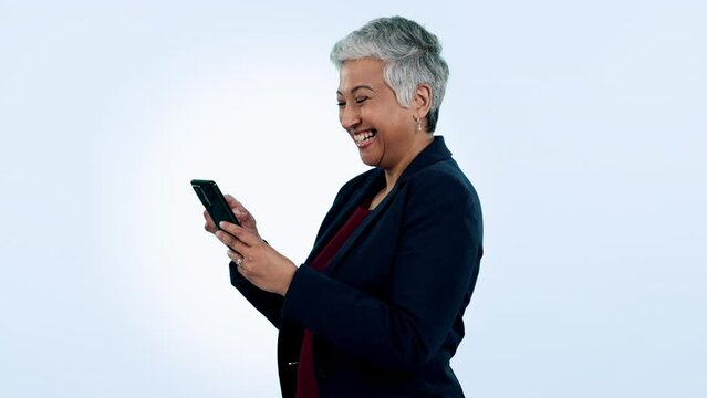 Happy, laugh and senior business woman with phone in studio for funny, text or chat on blue background. Smartphone, app and elderly female ceo with online comic, social media or gif communication