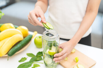 Vegetable smoothie detox, woman hand making healthy raw fresh green fruit juice with blender...