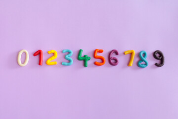 Set of Handmade Plasticine Numbers on a Purple Background. Collection of math figures made by hand from play dough 
