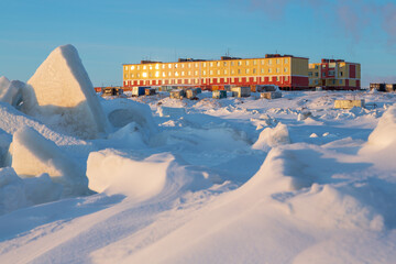 Colorful residential buildings on the coast of the frozen sea. Northern settlement in the Arctic....