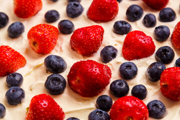 Fresh juicy strawberries and blueberries blueberries in thick whipped cream close-up