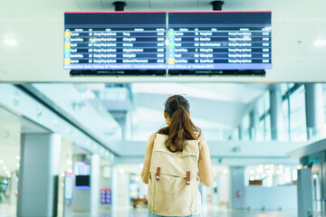 Happy beautiful Asian female backpacker tourist standing and looking at flight departure and...