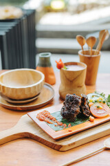 Indonesian food iga bakar or grilled ribs served on wooden plate with vegetable, sambal sauce, and strawberry juice