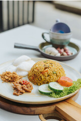 Indonesian food nasi goreng or fried rice served with abon chicken floss, kerupuk crackers, and vegetables