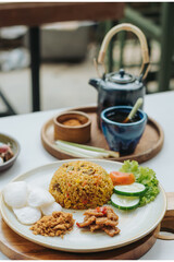 Indonesian food nasi goreng or fried rice served with abon chicken floss, kerupuk crackers, and vegetables