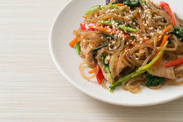 japchae or stir-fried Korean vermicelli noodles with vegetables and pork topped with white sesame