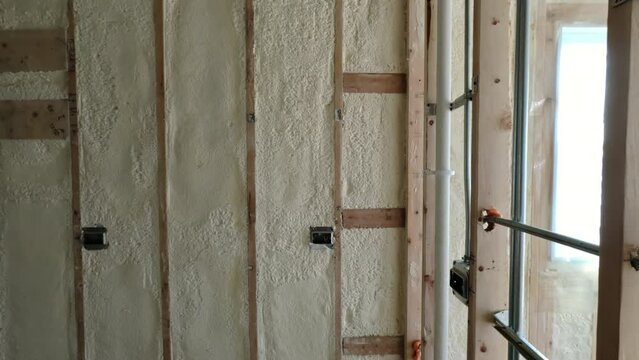 Environmentally friendly housing insulation covering a house. insulation fills up a frame on a wooden wall house under construction. Wide shot