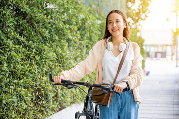 Fototapeta na wymiar Asian young woman walking alongside with bicycle on summer in park countryside outdoor, Happy female smiling walk down the street with her bike on city road, ECO environment, healthy holiday travel