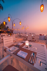 Luxury hotel resort outdoor restaurant at beach. Led lights candles and romantic wooden tables,...
