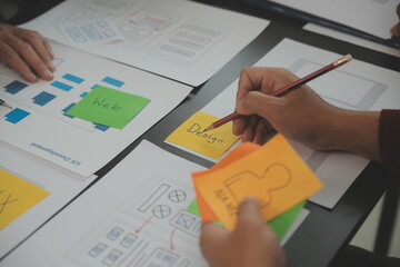 Close up ux developer and ui designer brainstorming about mobile app interface wireframe design on...