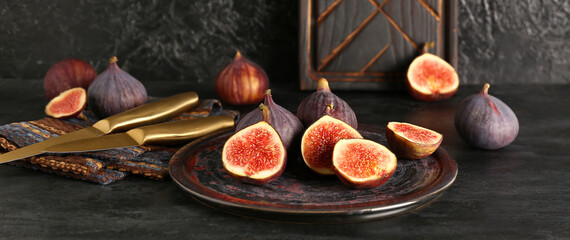 Plate with fresh ripe figs on black background