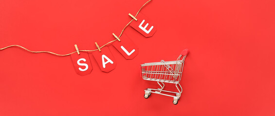 Shopping cart and word SALE on red background