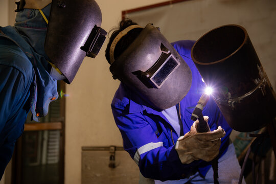 A man is training to be a welder and another person is in charge of the examination. Welder are assembling the workpiece by Tungsten Inert Gas Welding process (TIG).