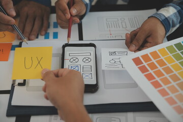 Close up ux developer and ui designer brainstorming about mobile app interface wireframe design on...