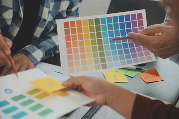 Close up ux developer and ui designer brainstorming about mobile app interface wireframe design on table with customer breif and color code at modern office.Creative digital development agency