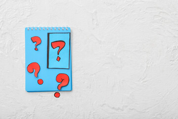 Fototapeta na wymiar Notebook with quiz card and question marks on white background