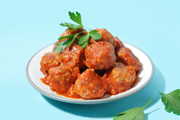 Plate of tasty meat balls with sauce on blue background