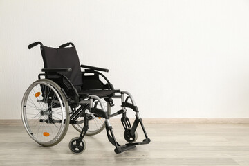 Fototapeta na wymiar Modern empty wheelchair near white wall