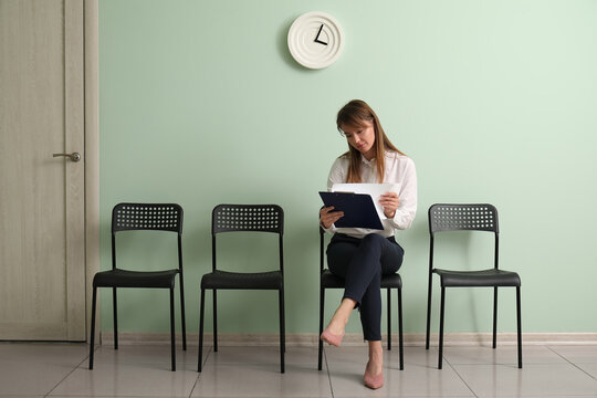 Female applicant with clipboard waiting for job interview in room