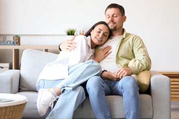 Happy young couple hugging on sofa at home