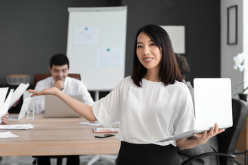 Female Asian business consultant with laptop working in office