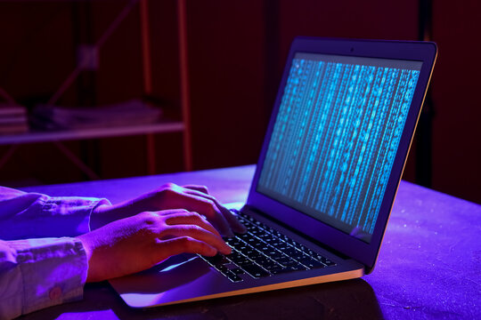 Female programmer typing on laptop keyboard at night in office, closeup