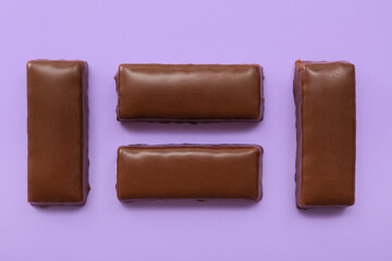 Tasty chocolate covered coconut candies on lilac background