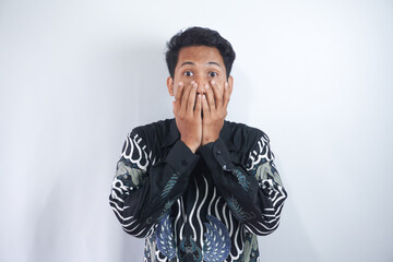 surprised young man wearing batik shirt covering his mouth