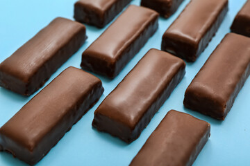 Tasty chocolate covered coconut candies on blue background