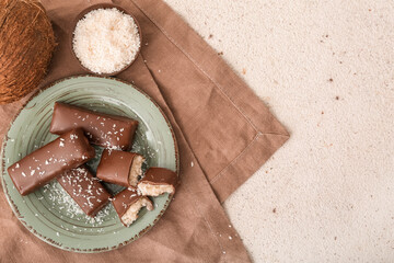 Plate with tasty chocolate covered coconut candies on light background