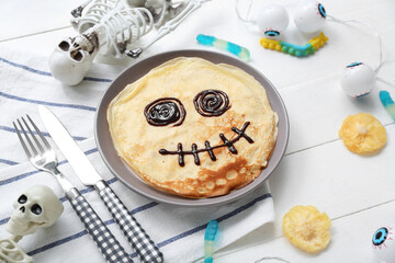 Composition with funny Halloween pancakes and decorations on light wooden background