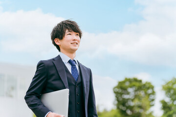 青空と若いスーツ姿のビジネスマン・新入社員・転職・就職活動
