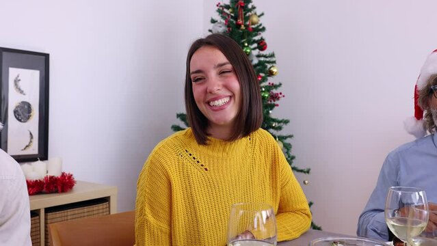 Young beautiful woman having fun celebrating christmas dinner with family or friends at home. Smiling pretty adult female enjoying xmas party celebration on winter vacation. Thanksgiving day.