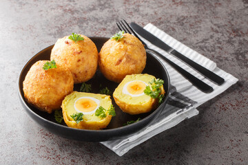 Delicious potato balls stuffed with boiled egg and then fried close-up in a plate on the table. Horizontal