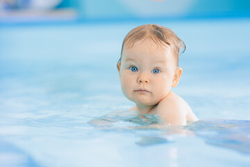 Fototapeta na wymiar Teaching small swimmer happy baby girl in swimming pool. Concept healthcare sport for infant
