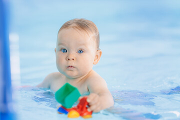 Fototapeta na wymiar Portrait happy baby girl play with toy in swimming pool, teaching small swimmer. Concept healthcare sport for infant