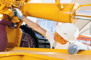 Machinery tractor mechanic checks hydraulic hose system equipment on excavator
