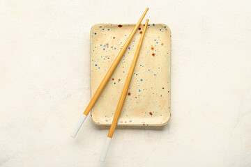 Chinese chopsticks and plate on light background