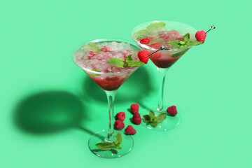 Glasses of fresh raspberry mojito on green background