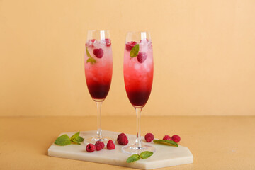 Board with glasses of fresh raspberry mojito on yellow background
