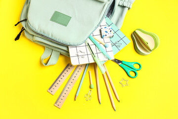 Stylish school backpack with different stationery supplies on yellow background