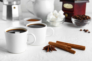 Obraz na płótnie Canvas Cups of tasty coffee coffee with cinnamon on white background