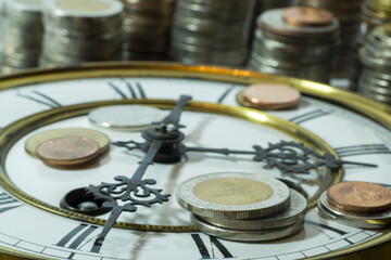 stack of coins and old clock