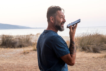 Tourist speaking at the phone in outdoor travel destination leisure activity alone. Ocean and beach island in background. Adventure traveler lifestyle. Roaming outside. Holding cell speaking  speaker