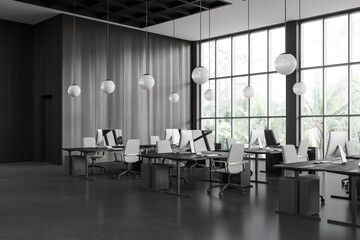 Dark workspace interior with desk and pc monitors in row, panoramic window