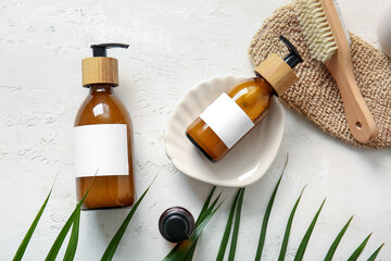 Bottles of shampoo, brush and loofah on white background