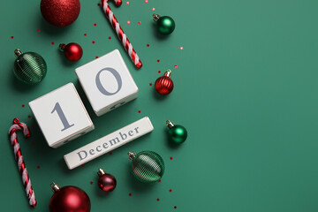 Calendar with date 10 DECEMBER and Christmas decor on green background