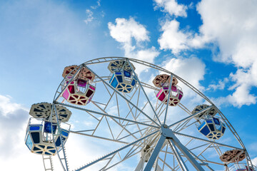 Ferris wheel against a blue sky with white clouds. Amusement park. © Elly Miller