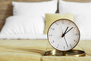 Golden alarm clock on bed in room, closeup